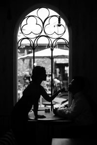 Side view of mother and daughter sitting on window