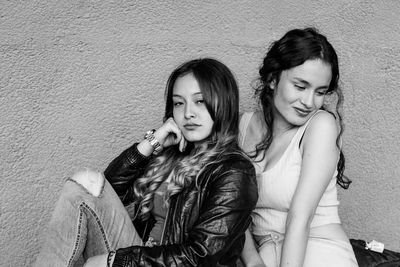 Young siblings sitting against wall