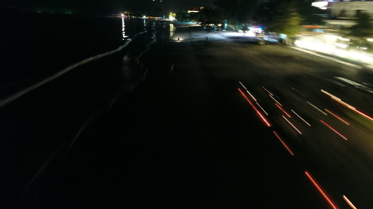 ILLUMINATED LIGHT TRAILS ON ROAD IN CITY AT NIGHT