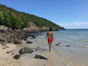 Rear view of woman on beach against sky