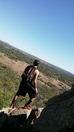 Rear view of hiker standing on rock formation against landscape