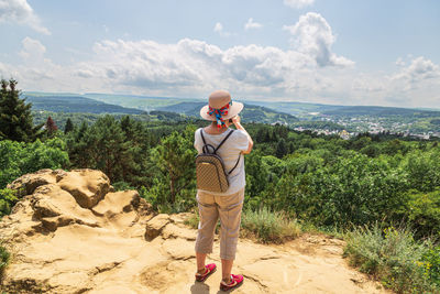 Rear view of man standing on rock against sky