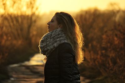 Side view of young woman looking at sunset