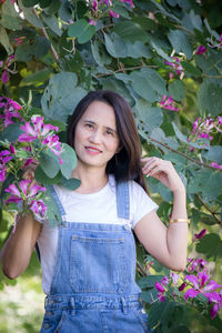 Portrait of a smiling young woman standing against plants