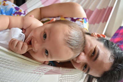 Portrait of mother and baby relaxing in hammock at home