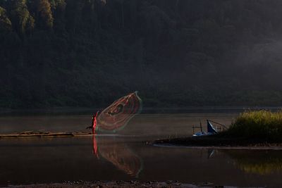 Full length of person throwing fishing net in lake