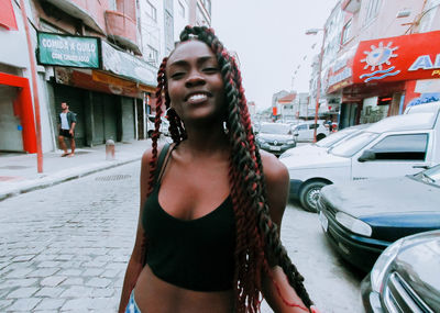 Happy young woman standing on street in city