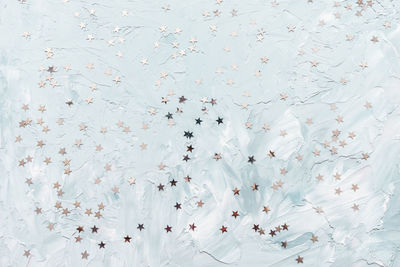 Trendy silver foil confetti stars on white and blue light background. winter abstract backround