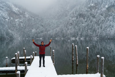 Man standing on pier over lake against mountains during winter