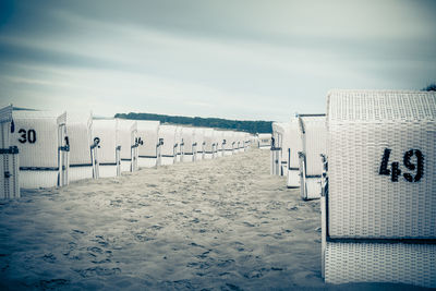 Hooded chairs on beach against sky