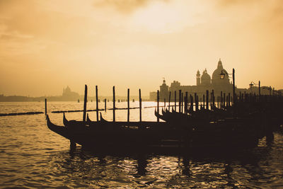 Boats moored in canal against sky during sunset