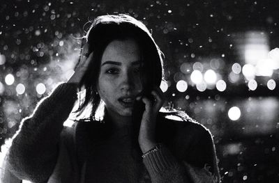 Portrait of woman standing against illuminated snow at night