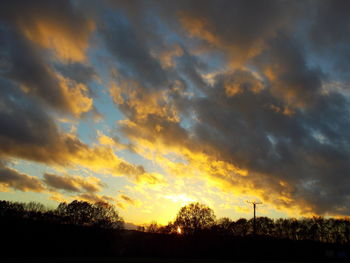 Low angle view of silhouette trees against dramatic sky