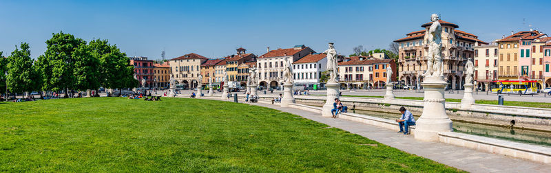 People in park by buildings against sky in city