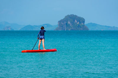 Man in sea against blue sky