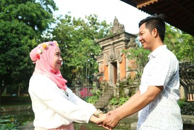 Side view of couple dancing while standing in park