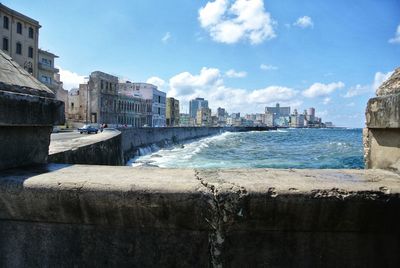 Sea by buildings against sky in city