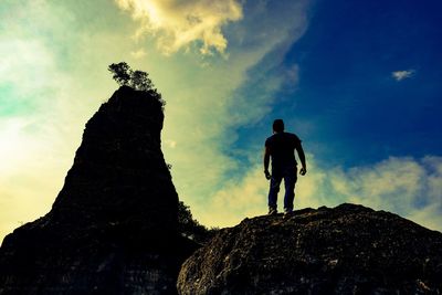 Man walking on rock against sky
