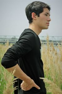 Side view of young man looking away on field