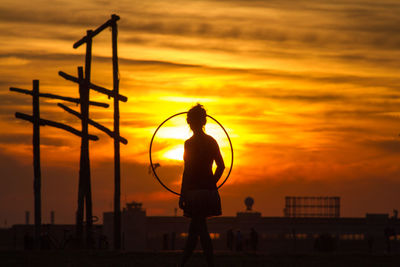 Silhouette woman with plastic hoop during sunset