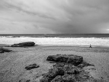 View of calm beach against cloudy sky