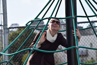 Portrait of a woman standing on chainlink fence