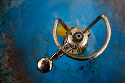 Close-up of metal hanging against blue wall