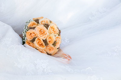 Cropped image of bride wearing white wedding dress with bouquet