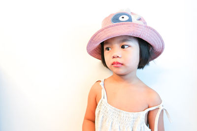 Cute girl looking away while standing against white background