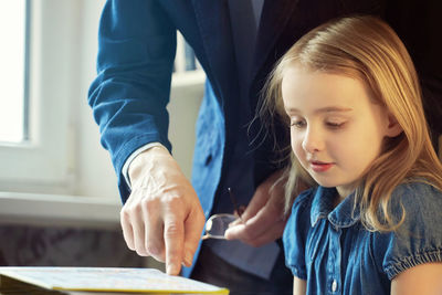 Midsection of father explaining homework to daughter at home