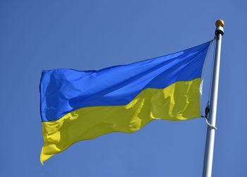 Low angle close up view of ukrainian flag against clear blue sky