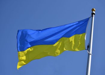 Low angle view of flag against clear blue sky