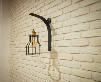 Light bulb hanging against brick wall