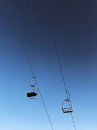 Low angle view of ski lifts against blue sky