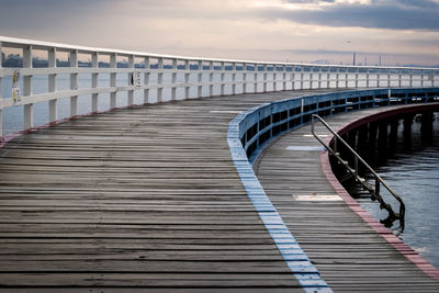 Empty wooden pier in sea during sunset