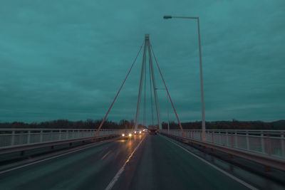 Cars on bridge against sky at dusk