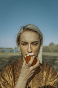 Portrait of woman eating apple against clear sky