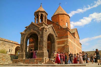 Group of people outside historic building against sky