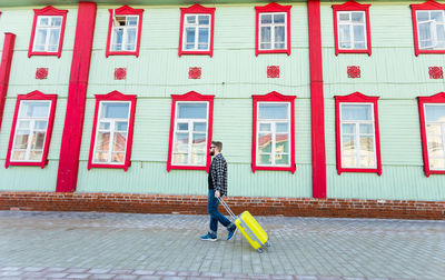 Woman walking on footpath against building in city