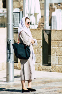 Full length of woman standing against building in city