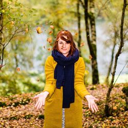 Portrait of woman throwing autumn leaves at forest