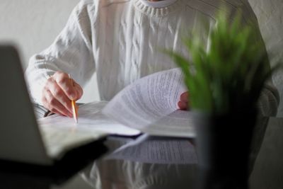 Midsection of woman holding paper