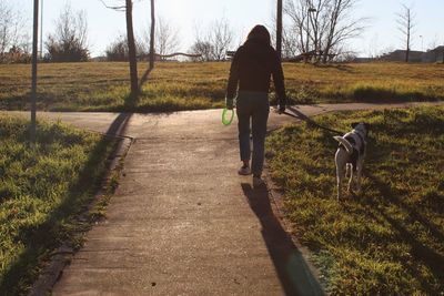 Rear view of woman with dog walking on field