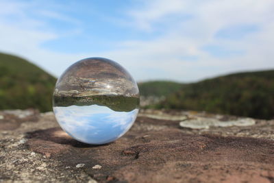 Close-up of crystal ball on land against sky