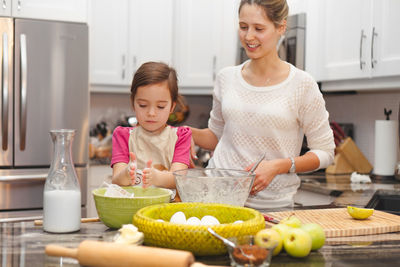 Happy mother and daughter standing at home