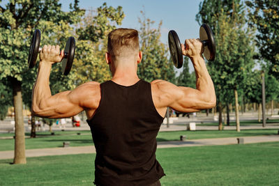 Rear view of man with arms raised in park