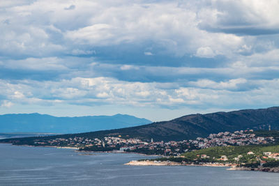 Scenic view of sea by townscape against sky