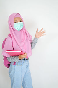 Midsection of woman standing against pink background