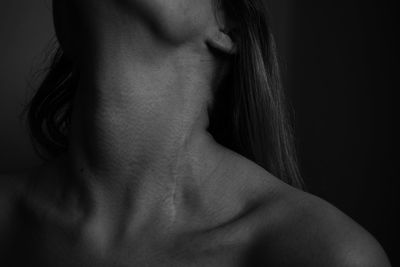 Close-up of shirtless woman against black background