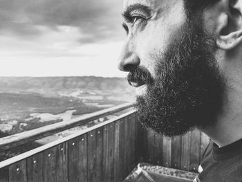 Close-up of bearded man at observation point looking away against sky